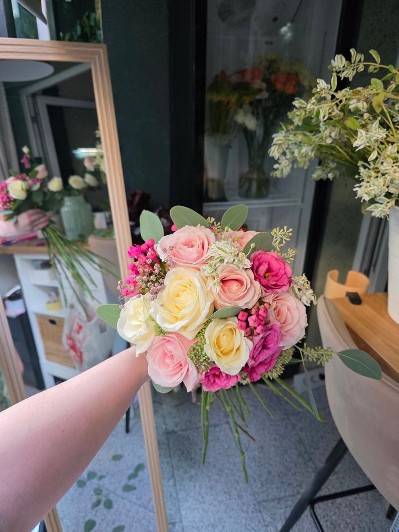 Buchet de mireasă rotund cu trandafiri roz și ivoire, lisianthus fucsia, bouvardia și frunze de eucalipt, ținut în mână